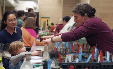 An instructor shows a plant root system to a small child during a science fair.