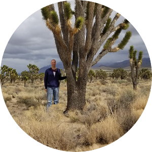 Gary Deters standing next to a Joshua Tree in the desert.