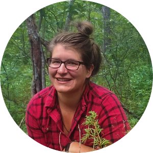 Portrait of Katrina Freund Saxhaug wearing a red flannel shirt with a forest backdrop.