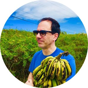 Professor Adrian Hegeman holding a bushel of bananas in a field. 