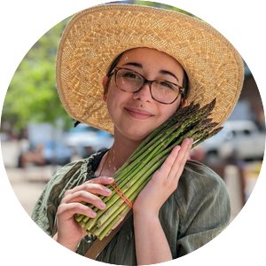 Portrait of Forest Hunt in a sun hat holding a bundle of asparagus. 