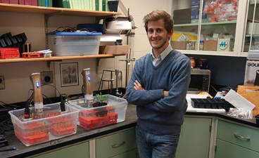 a man standing in a lab showing off a plant experiment 