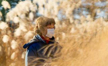 woman wearing a mask in the middle of a field of tan grass
