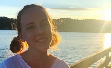 Adynn Stedillie smiling in front of a body of water during golden hour