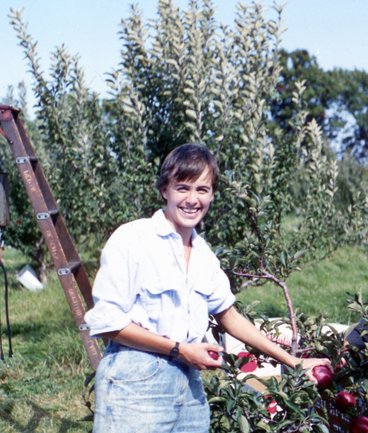 Dr. Hoover holding apples in an orchard in 1987